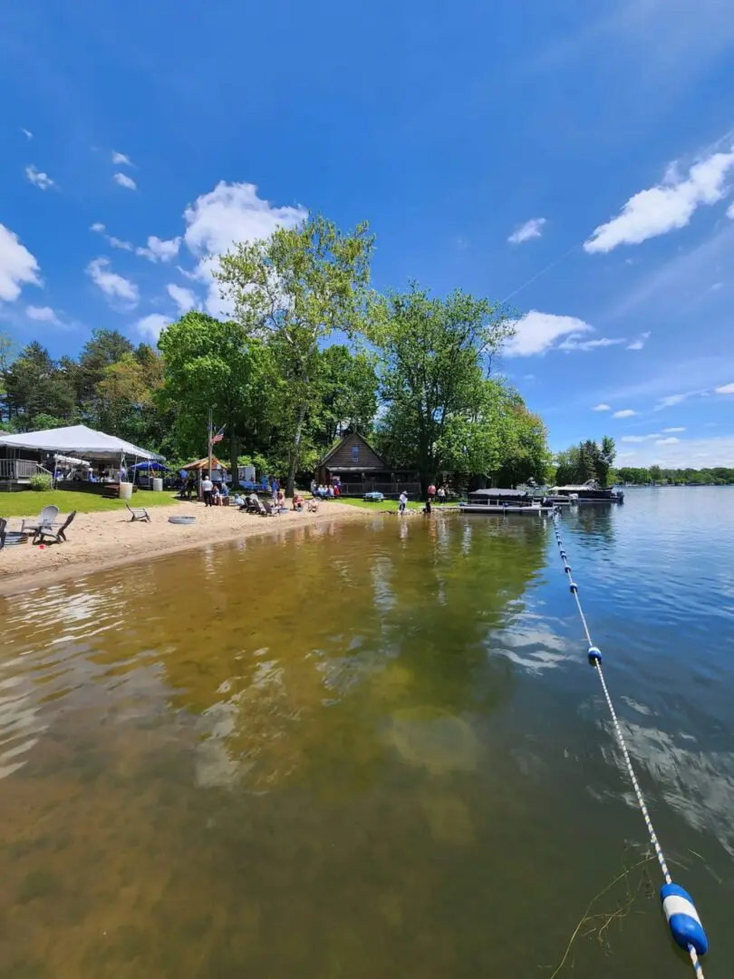 A beach with people sitting on it and boats in the water.