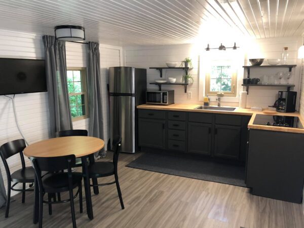 A kitchen with a table and chairs, refrigerator, microwave, sink, and cabinets.