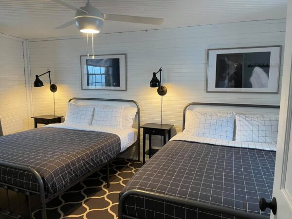 A room with two beds and lamps on the wall.