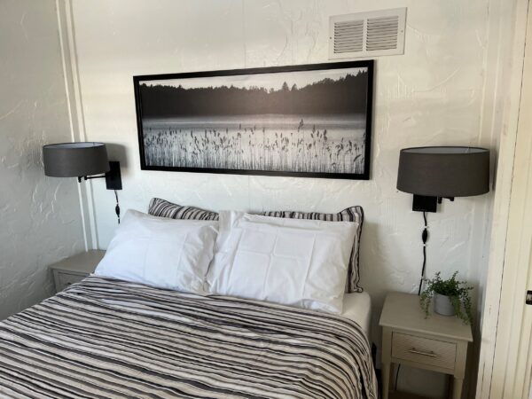 A bed room with two lamps and a picture on the wall