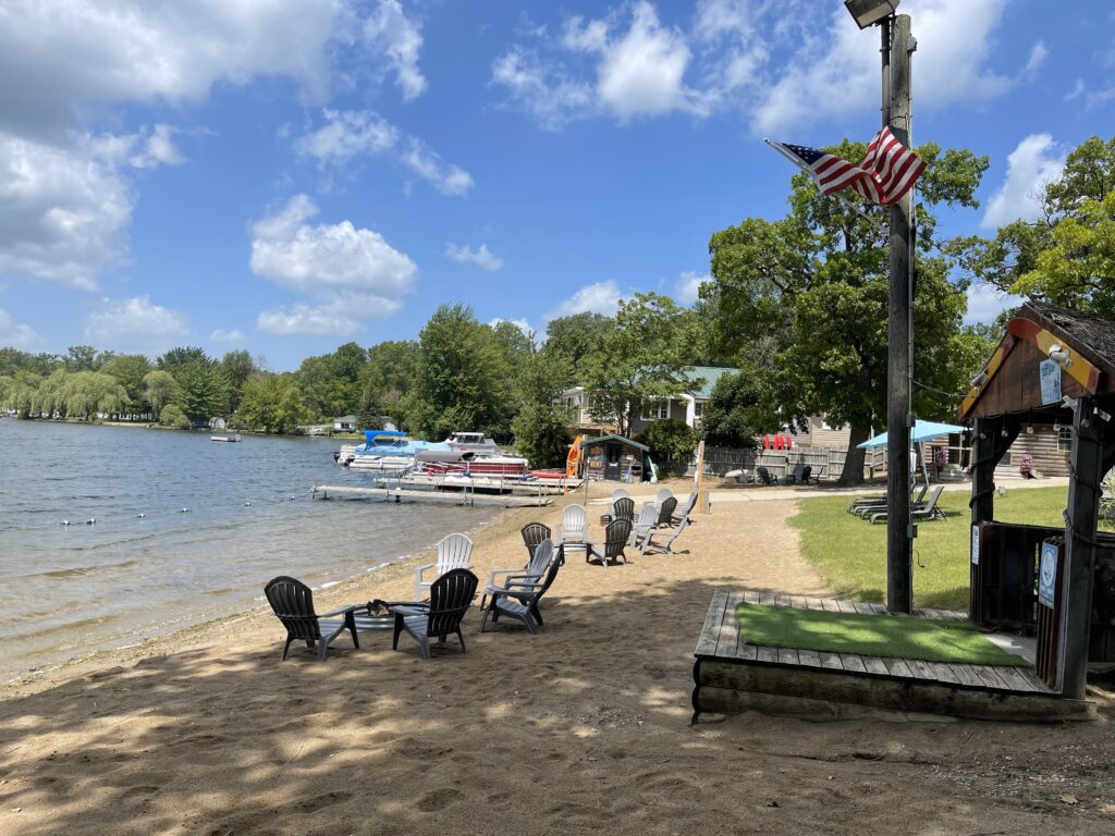 A beach with chairs and boats on the water.