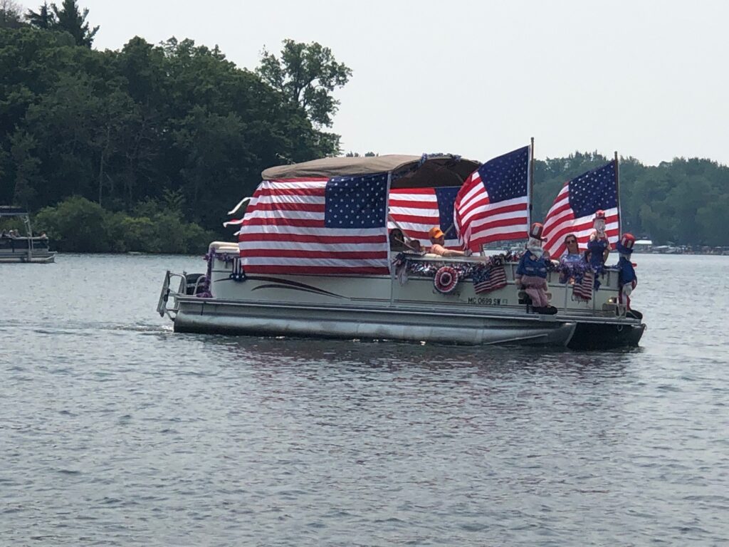 A boat with american flags on it floating down the river.